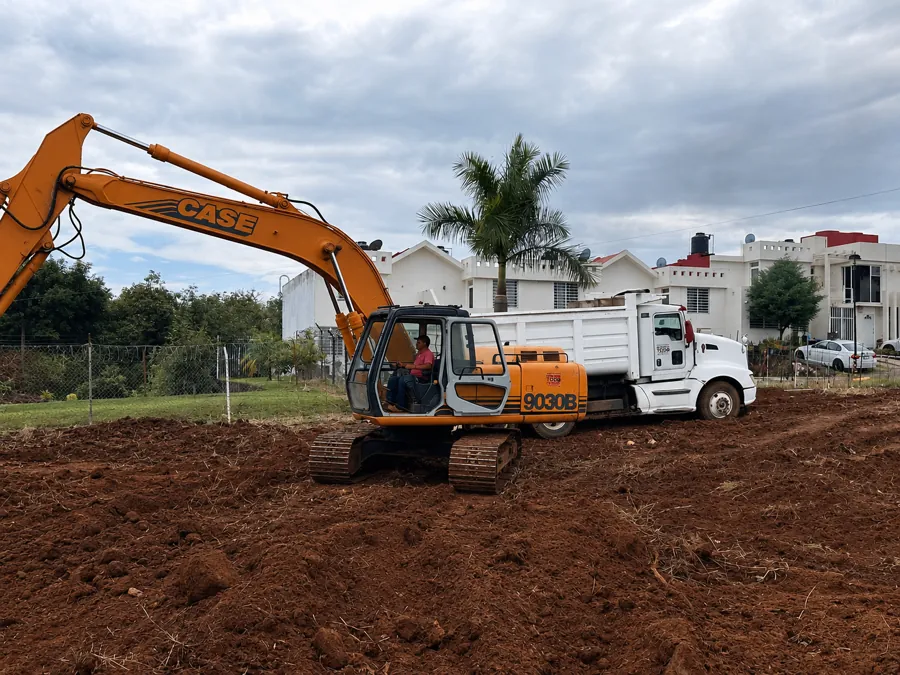 Excavadora y camión de volteo trabajando en el despalme de un terreno